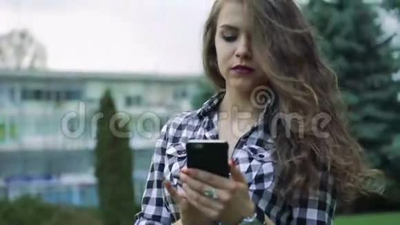 可爱的女孩用电话在漂亮的背景下微笑视频的预览图