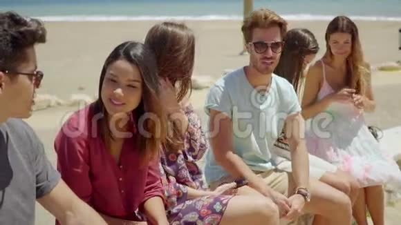 六个穿短裤的青少年朋友在海滩上社交视频的预览图
