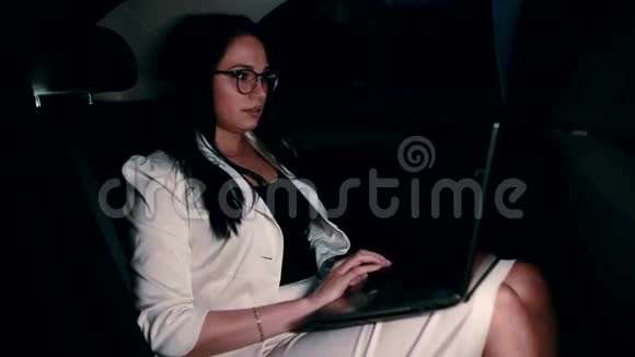 出租车上的女人晚上在车里的笔记本电脑上工作视频的预览图