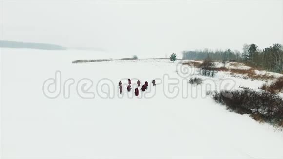一群穿着头巾的僧侣在森林中的冬季雪道上行走鸟瞰录像视频的预览图