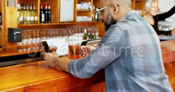 男子在4k柜台喝啤酒时使用手机视频的预览图