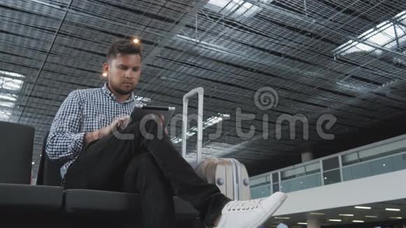 英俊的年轻人拿着平板电脑在机场工作技术旅行理念视频的预览图