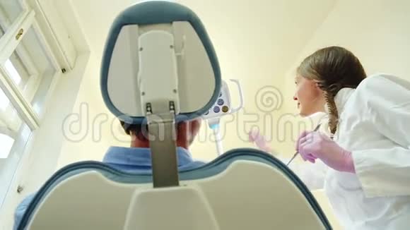 友好的女牙医打开灯检查病人的牙齿视频的预览图