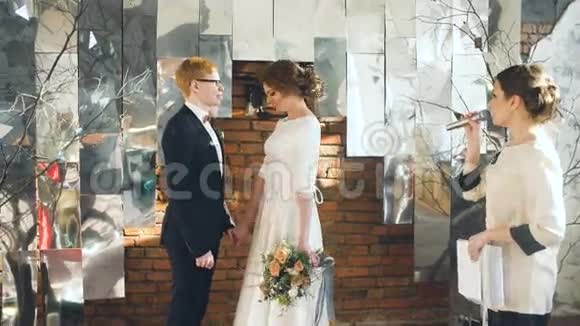 新娘和新郎在婚礼上亲吻登记员致辞后室内庆祝活动视频的预览图