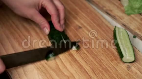 女用手用刀在木板上切一根新鲜黄瓜视频的预览图