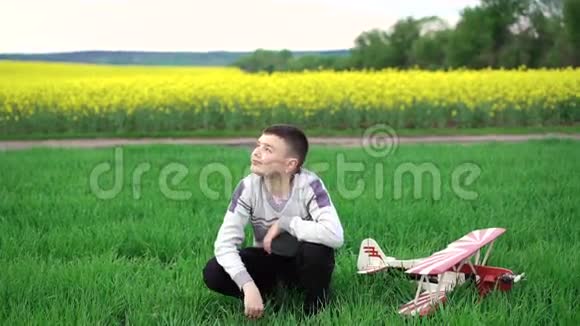 可爱的男孩和自制的直升机坐在小麦上看着天空4k视频的预览图