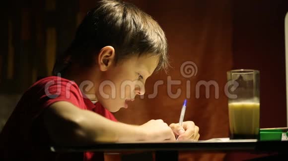 桌子旁的男孩在笔记本上写字视频的预览图