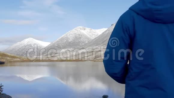 一个人站在山上的高处欣赏着美丽的景色它周围有山峰和美丽的视频的预览图