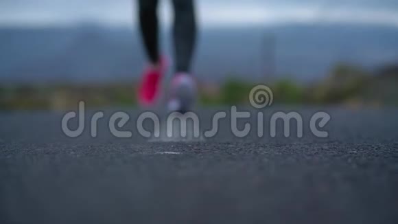跑鞋在山区的沙漠道路上系鞋带的女人慢动作视频的预览图