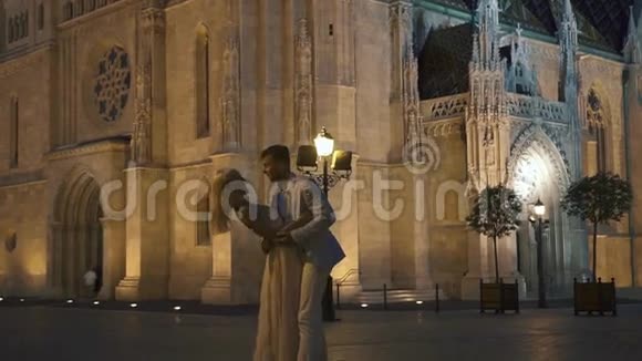 在炎热的夏季夜晚华丽的新婚夫妇在壮丽的布达佩斯背景中轻轻拥抱视频的预览图