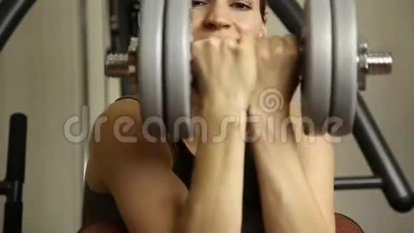 年轻女子参加体育运动在健身房健身拿着哑铃做运动的女孩视频的预览图