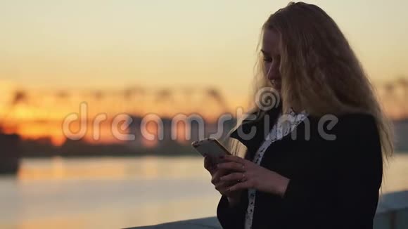 背倚河堤围栏城市的日落慢动作视频的预览图