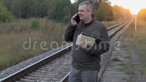 有智能手机和书籍的人走在铁路附近视频的预览图