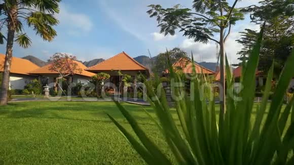 绿色的草坪和白色的小房子有橙色的瓷砖屋顶通过小径连接在一起视频的预览图