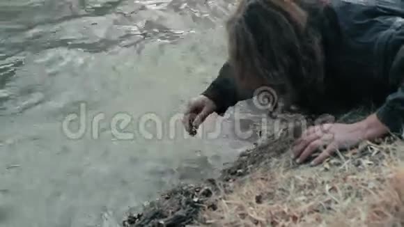 一个无家可归的乞丐躺在河边洗了手和脸视频的预览图