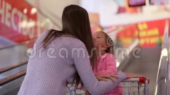 母亲带着女儿坐无轨电车坐自动扶梯到超市的下一层视频的预览图