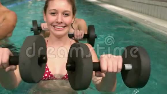健身小组使用的重量在游泳池微笑的相机视频的预览图