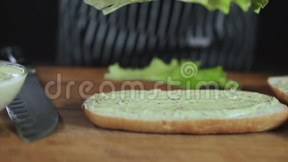 厨师把沙拉叶放在三明治上视频的预览图