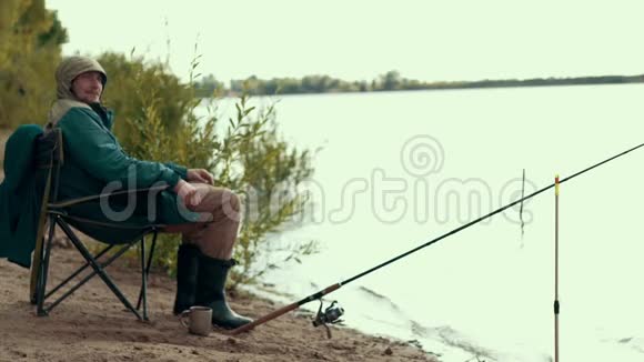 渔夫坐在河边的椅子上几乎是钓竿等待着咬人视频的预览图