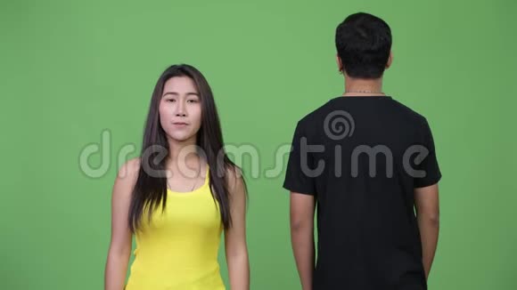 年轻的亚洲女人年轻的亚洲男人看着后面视频的预览图