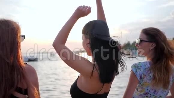 聚会朋友在海滩上日落时跳舞女朋友在海边举起手臂年轻的女人跳舞视频的预览图
