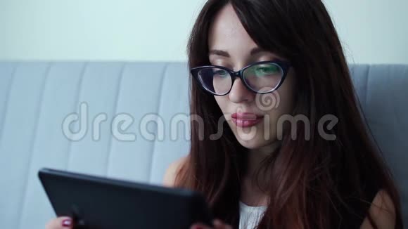 年轻有魅力的商务女性坐在家里做数码平板电脑视频的预览图