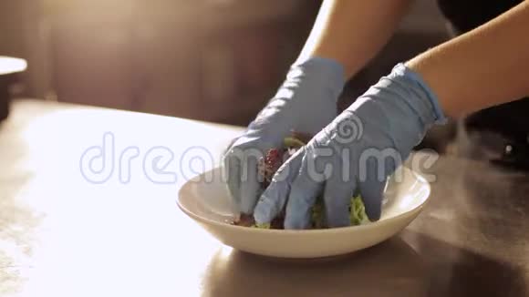 厨师手里的手套把碗里的沙拉放在盘子里视频的预览图