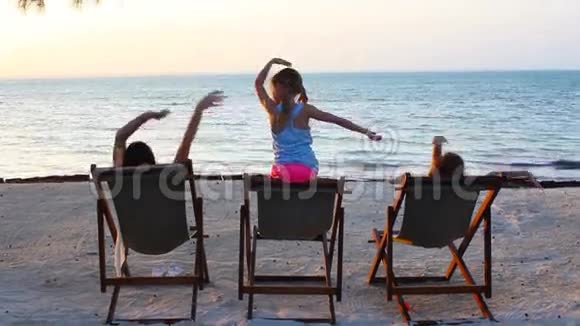 日落时分小女孩和妈妈坐在沙滩椅上视频的预览图