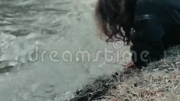 一个无家可归的乞丐躺在河边洗了手和脸视频的预览图