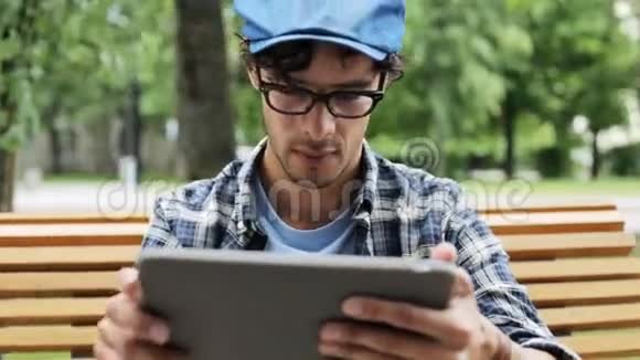 有平板电脑的人坐在城市街头的长凳上视频的预览图