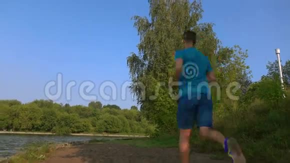 年轻男子奔跑在沙质夏日河畔后景4K放大视频视频的预览图