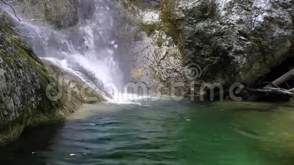 前面的瀑布在小山河流动在石质河床覆盖苔藓春天纯净的淡水视频的预览图