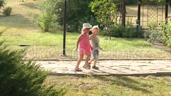 两个可爱的孩子在夏天公园的小巷里散步视频的预览图
