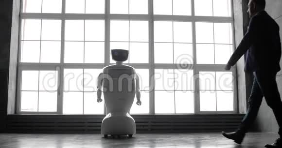 一个时尚的男人与机器人交流把一只塑料机械手臂按在机器人身上握手控制系统视频的预览图