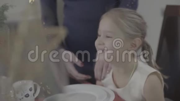 爱的母亲亲吻快乐兴奋可爱的女儿脸颊在节日的圣诞晚餐厨房装饰视频的预览图