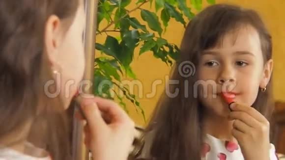 带口红的小女孩那孩子正坐在镜子旁女孩画了她的嘴唇视频的预览图