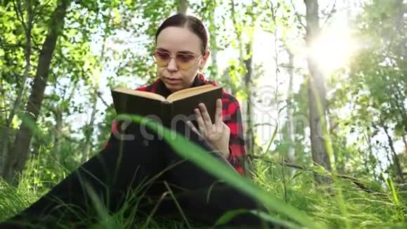 女人在绿色的夏日森林里看书视频的预览图
