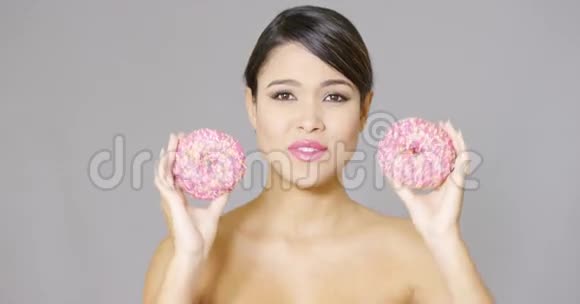 快乐活泼的女人拿着两个粉红色的甜甜圈视频的预览图