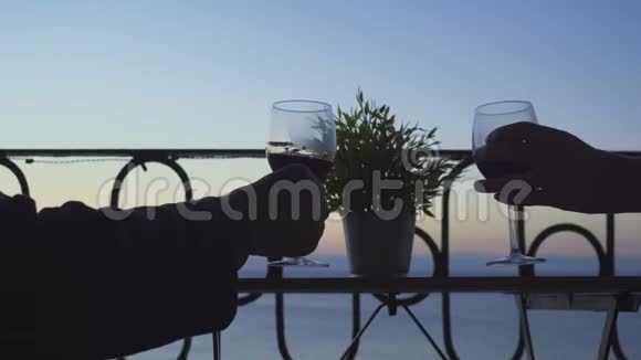一男一女坐在阳台上在大海的背景上喝着红酒特写镜头视频的预览图