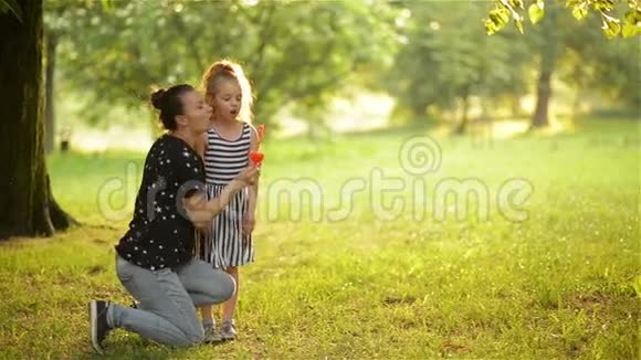 美丽的母亲和她的女儿在大自然中做肥皂泡笑视频的预览图