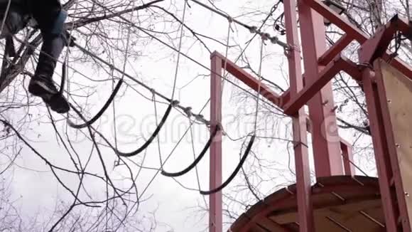 少年登山者走在极端公园的高绳道上的垂木桥旁视频的预览图