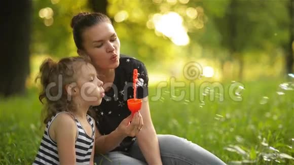 美丽的母亲和她的女儿在大自然中做肥皂泡笑视频的预览图