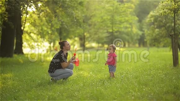 妈妈和女孩在户外吹肥皂泡父母和孩子在公园玩得很开心视频的预览图