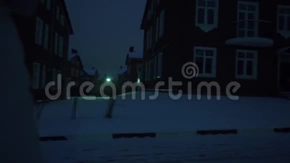 一个孤独的年轻女子穿着银色夹克晚上在住宅区的雪地上散步视频的预览图