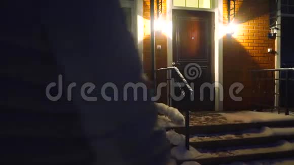 年轻女子穿着冬装晚上进入联排别墅慢动作视频视频的预览图