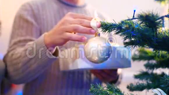 男人在圣诞树上挂球视频的预览图