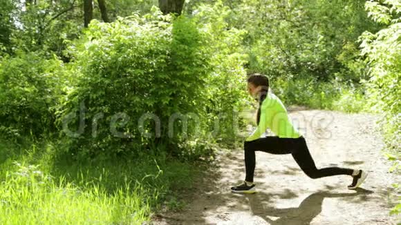 在森林附近的公园里做健身运动的年轻苗条的美女视频的预览图