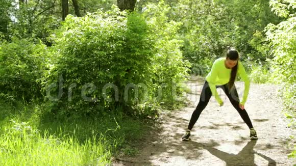 在森林附近的公园里做健身运动的年轻苗条的美女视频的预览图