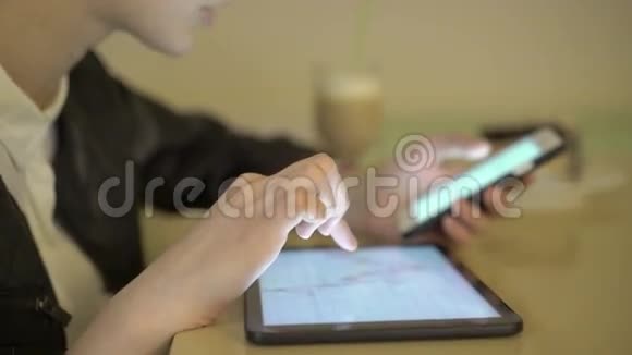 关闭女孩比较电话和平板电脑在咖啡馆的图表4K视频的预览图