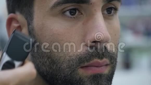 口渴的过程理发师给一个留胡子的年轻人理发的特写视频的预览图